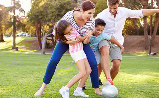 This image shows a family having fun together in a park. This image shows a family having fun together in a park.