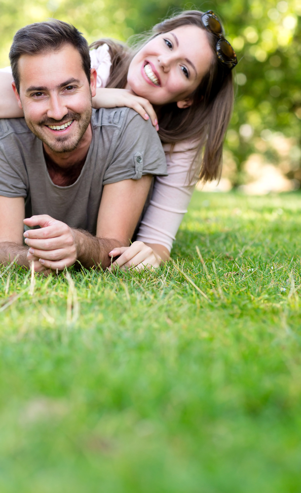 Playful couple smiling and lying at the park Playful couple smiling and lying at the park