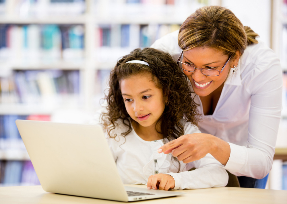 This image shows a schoolgirl and a teacher researching on a computer as part of an afterschool program.